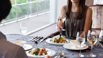 A dining table with plates of food, wine glasses, and cutlery.