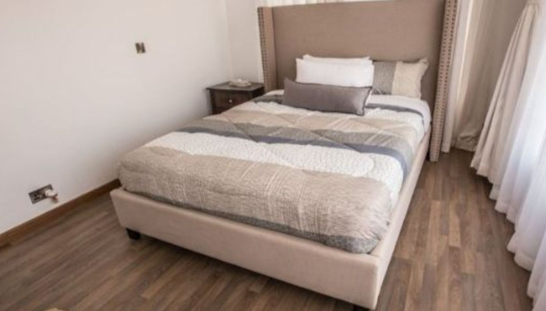 A bedroom with a large bed, a nightstand, and a headboard.