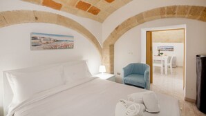 A bedroom with a bed, a chair, a table, and a painting on the wall. - GuestHost - NEW! Apt in the heart of Monopoli! 200m from sea! (Monopoli)