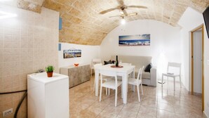A compact living space with a dining area, a kitchenette, a ceiling fan, and a view of the sea. - GuestHost - NEW! Apt in the heart of Monopoli! 200m from sea! (Monopoli)