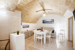 A compact living space with a dining area, a kitchenette, a ceiling fan, and a view of the sea.