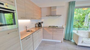 A modern kitchen with stainless steel appliances, a built-in oven, and a gas stove. There is a window with a view of greenery outside.