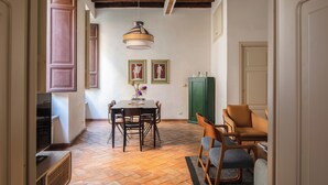 A dining area with a wooden table, chairs, and a hanging light fixture. - Family Suite 4 bedrooms with Terrace (Roma)