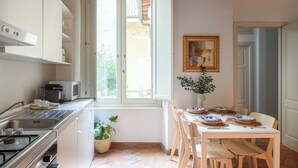 A kitchen with a window, a dining table set with plates, and a painting on the wall. - Family Suite 4 bedrooms with Terrace (Roma)