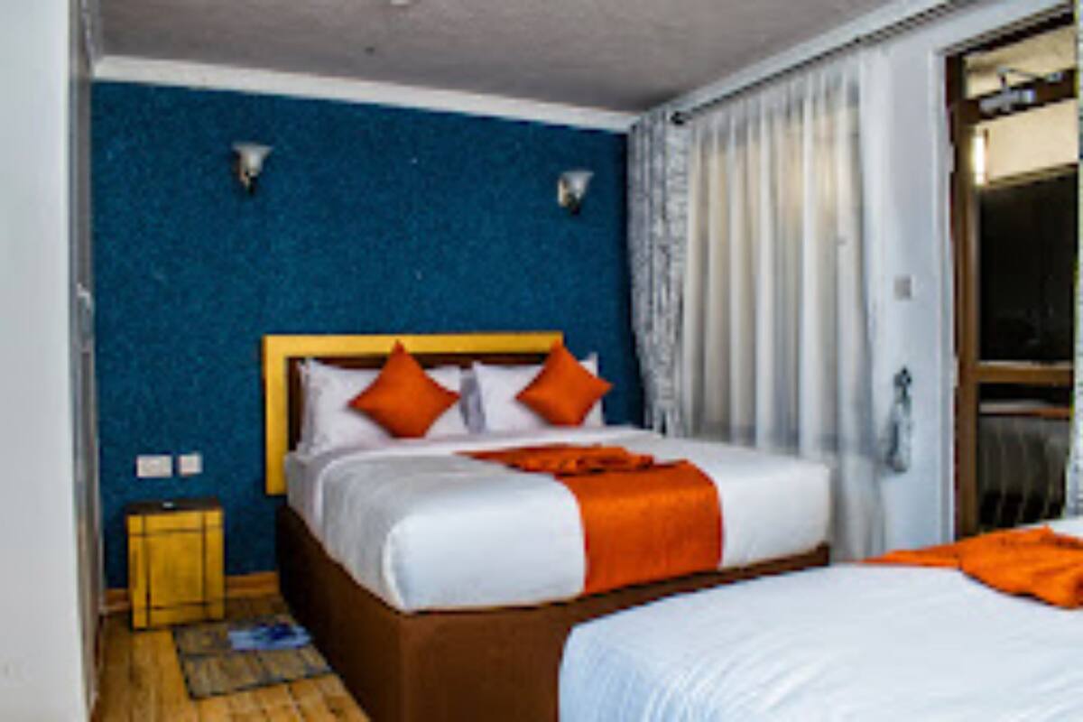 A hotel room with a large bed, a wooden headboard, and a blue accent wall.