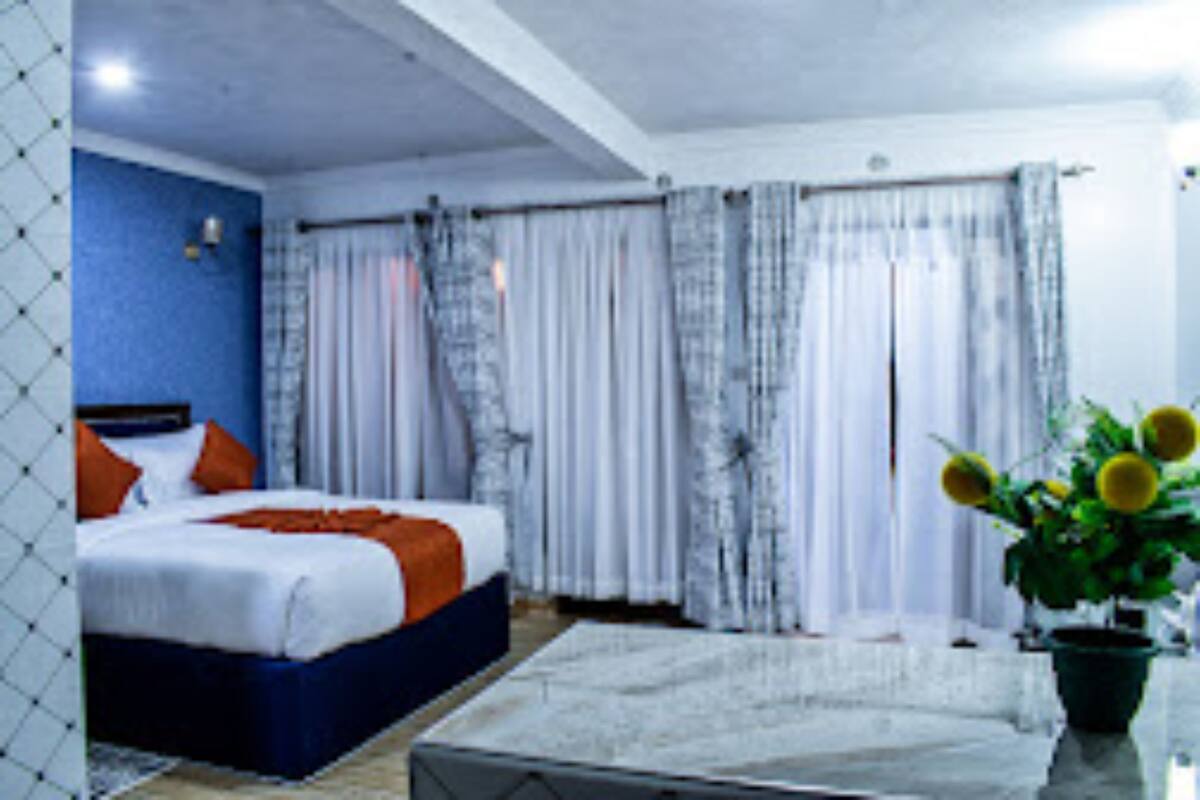 A bedroom with a bed, curtains, a potted plant, and a window.
