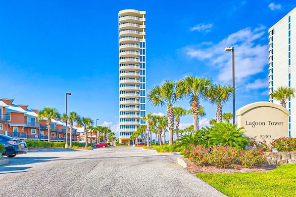 A modern hotel with a prominent tower, a well-maintained lawn, and a clear sky.