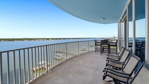 Un balcón con vista al agua, barandillas de metal y mobiliario exterior.