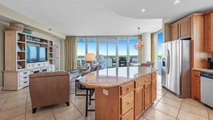 Una cocina amplia con una isla grande, armarios de madera y un refrigerador empotrado.