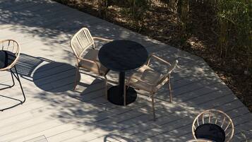 Eine Terrassengaststätte mit runden Tischen und Korbstühlen, umgeben von Bambuspflanzen.