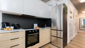 A modern kitchen with white cabinets, a stainless steel refrigerator, a built-in oven, and a coffee maker. - Spacious Apartment | 3 Bedrooms, Air Conditioning, Parking (Gdynia)