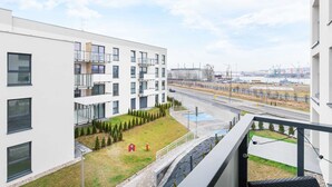 A modern building with multiple balconies and a view of a road with a bridge in the distance. - Spacious Apartment | 3 Bedrooms, Air Conditioning, Parking (Gdynia)