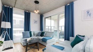 A modern living room with a sofa set, a coffee table, and a lamp. - Spacious Apartment | 3 Bedrooms, Air Conditioning, Parking (Gdynia)