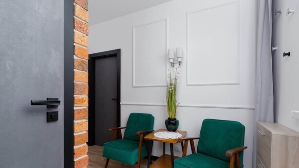 A room with two green armchairs, a small wooden table, a potted plant, and a cabinet. - Apartment in a green area | Workspace (Kraków)
