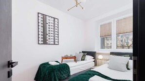 A modern hotel room with two beds, a large window, and a cityscape view. - Apartment in a green area | Workspace (Kraków)