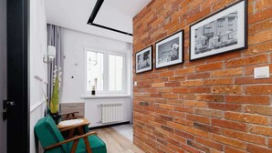 A room with a brick wall, a window, a chair, and a radiator. - Apartment in a green area | Workspace (Kraków)