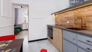 A modern kitchen with a brick backsplash, a stainless steel sink, and a wooden cabinet. - Apartment in a green area | Workspace (Kraków)