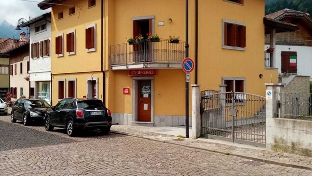 A yellow building with a red door labeled "Generali" and a sign indicating no parking. - Downtown apartment, pets allowed (Paularo)