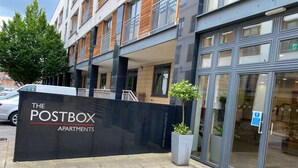 A modern building with a sign reading "The Postbox Apartments."