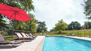 Ein Schwimmbecken mit Liegestühlen und einem roten Sonnenschirm.