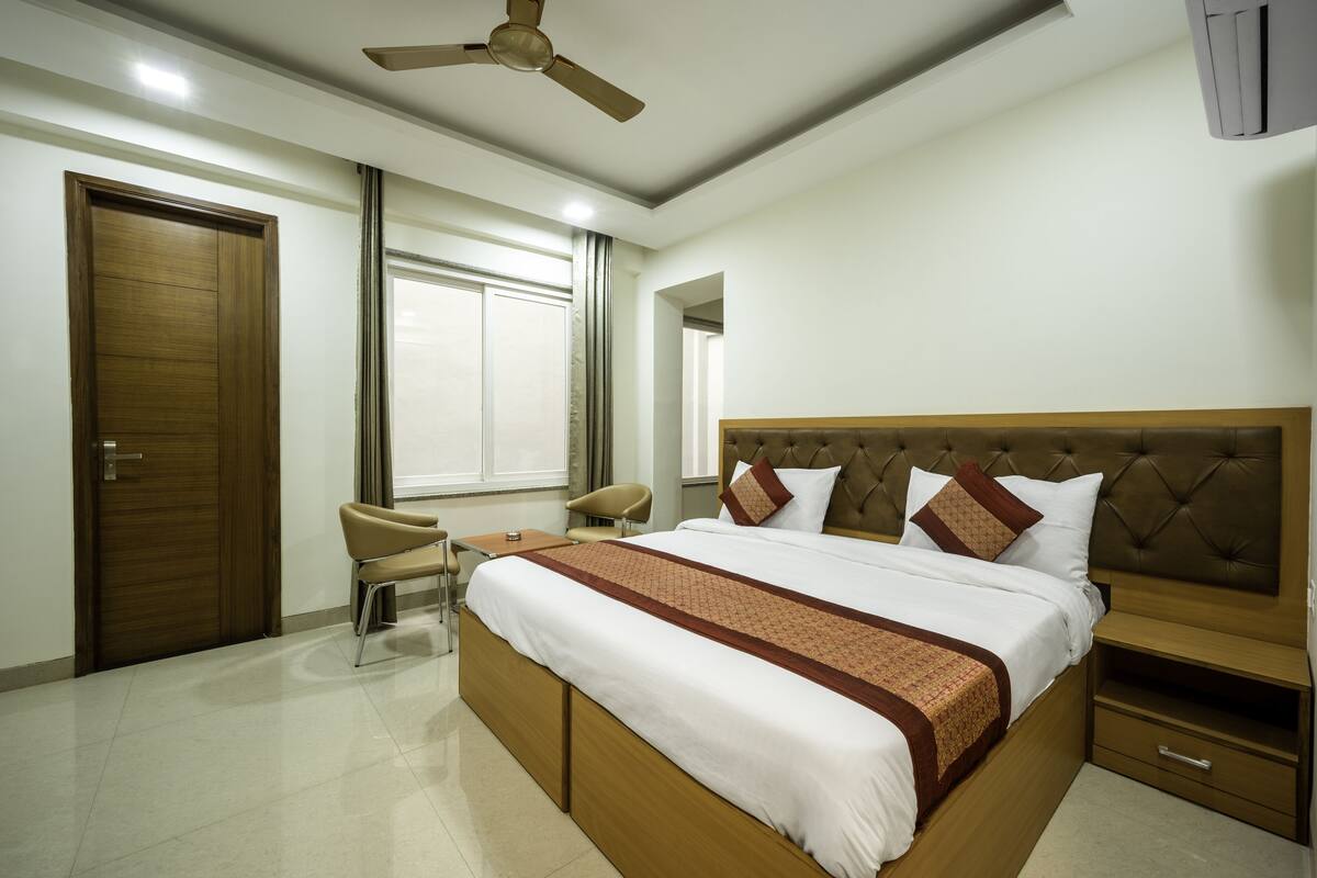 Una habitación de hotel con una cama grande, un escritorio, una silla y un ventilador de techo.