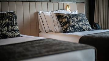 A hotel room with a modern bed, a headboard with a light fixture, and a telephone on the nightstand.