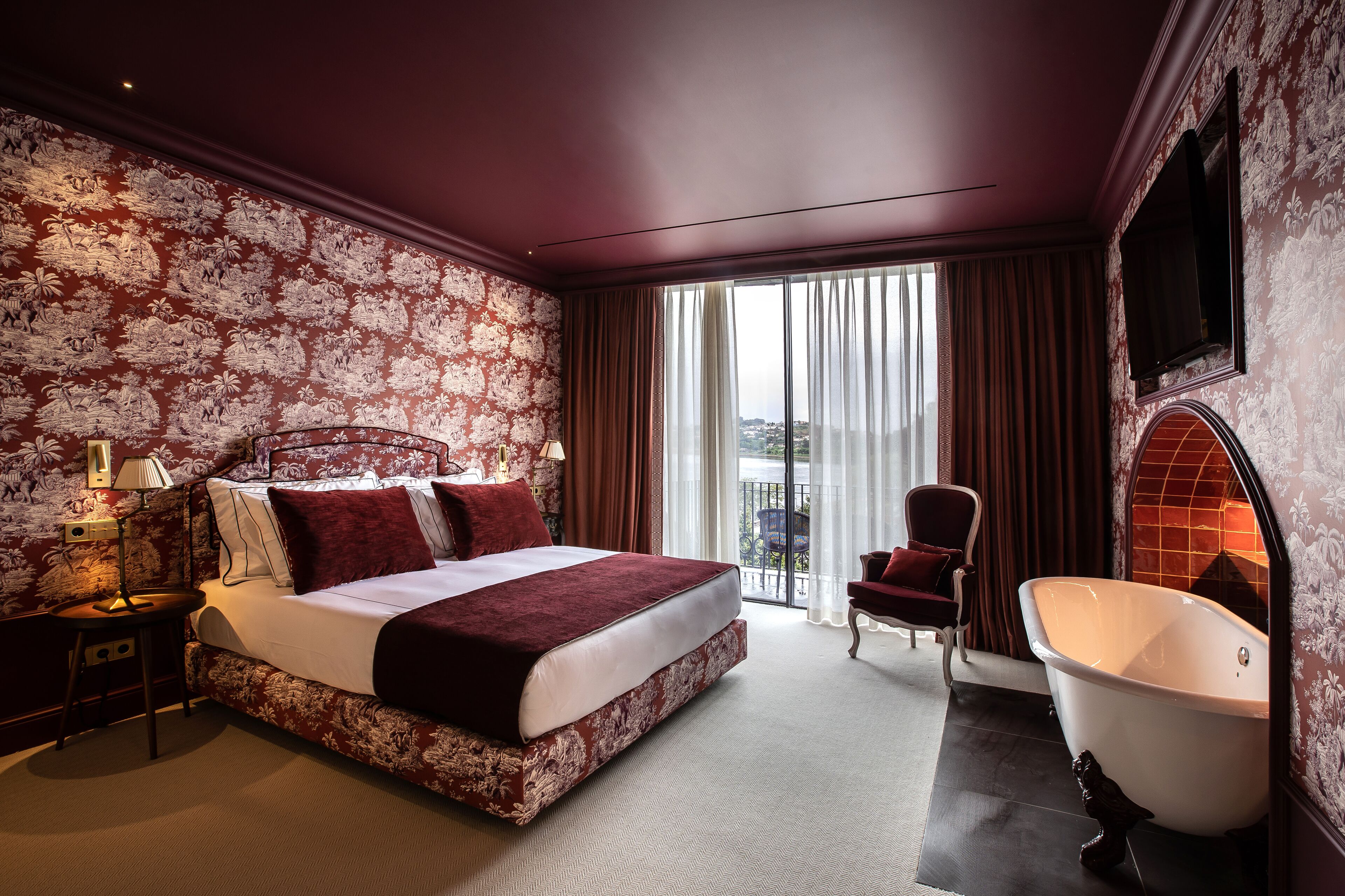 A spacious bedroom with a large bed, a sitting area, and a bathtub.