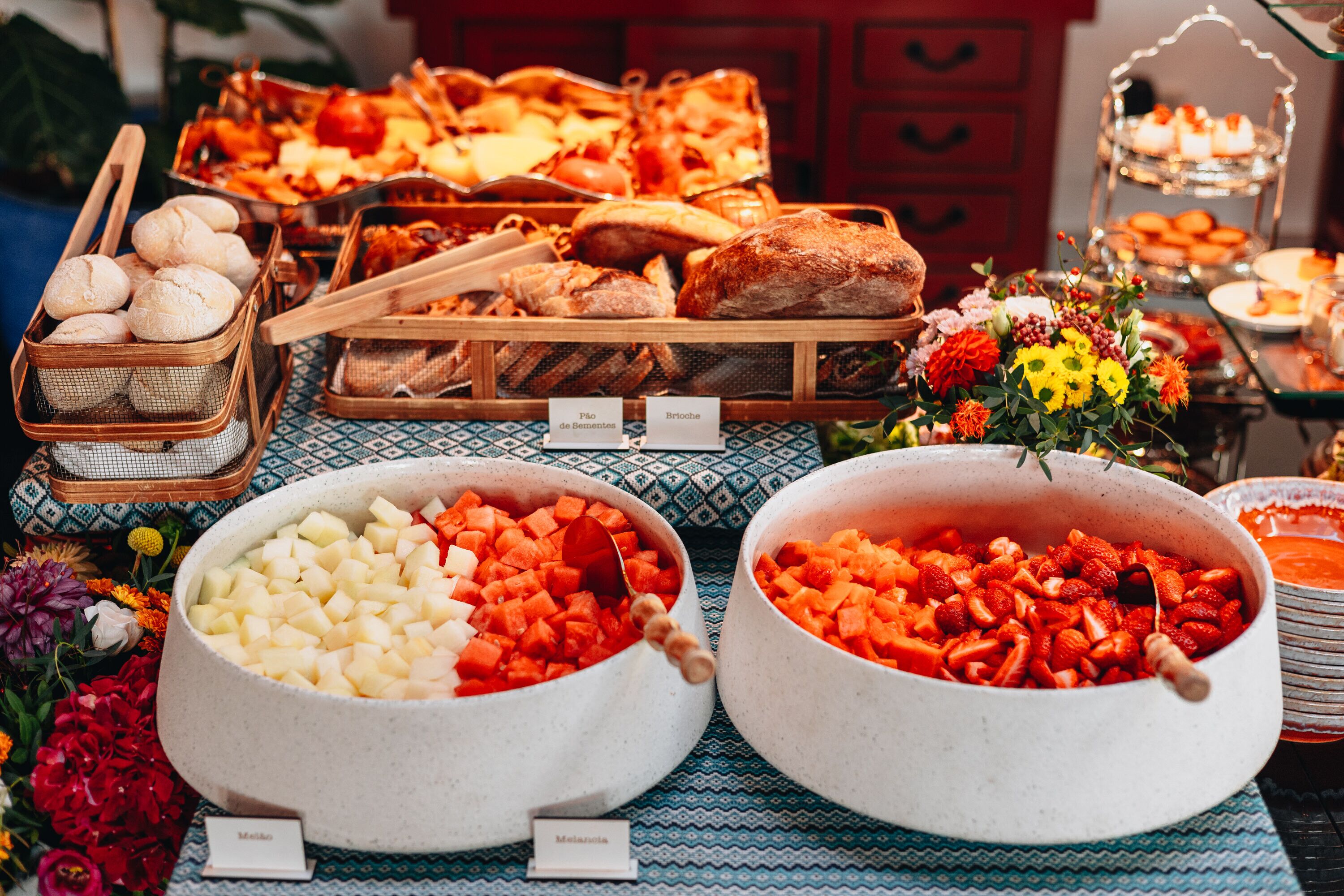 A buffet table with various food items and a floral arrangement.