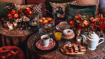 Uma mesa posta com doces, chá e um arranjo floral.