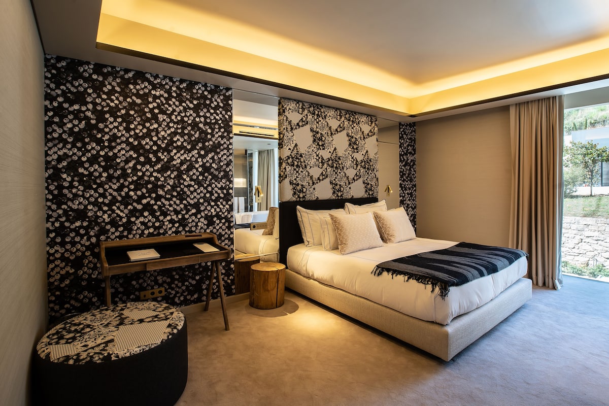 Une chambre à coucher moderne avec un grand lit, une petite table et un banc.