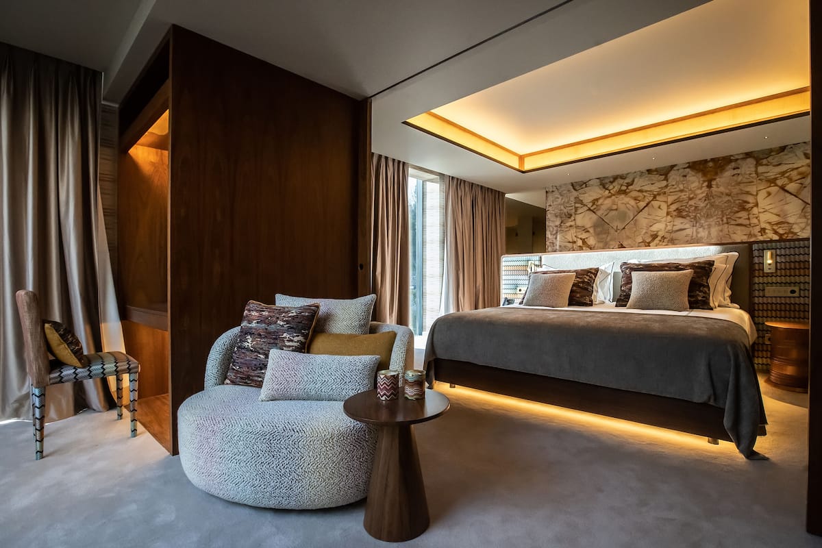 Une chambre moderne avec un grand lit, un canapé, un fauteuil et une petite table.