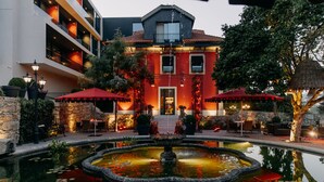 A hotel with a pool, outdoor seating, and a fountain.