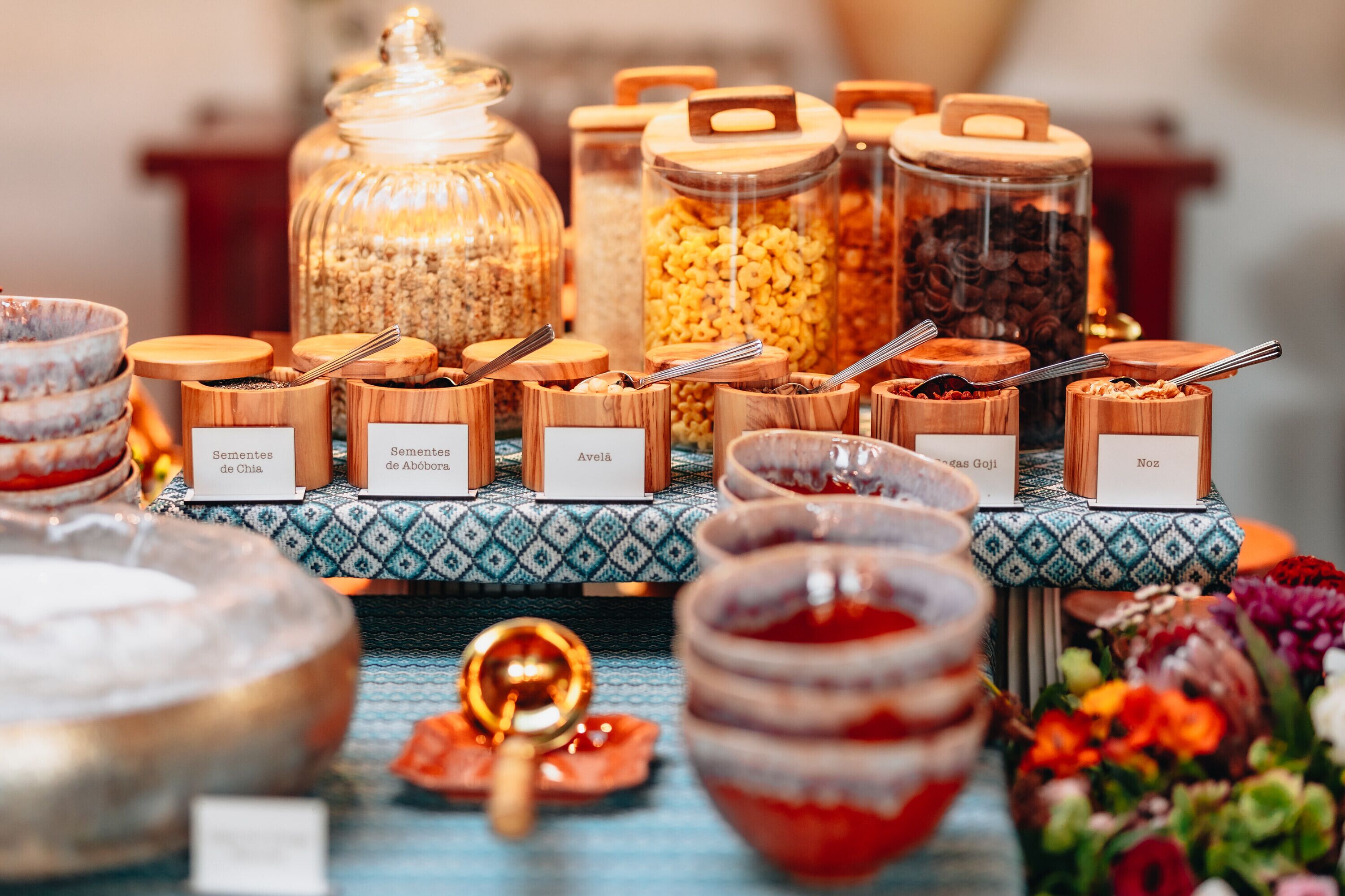 A buffet with labeled containers of various food items, including seeds and grains.