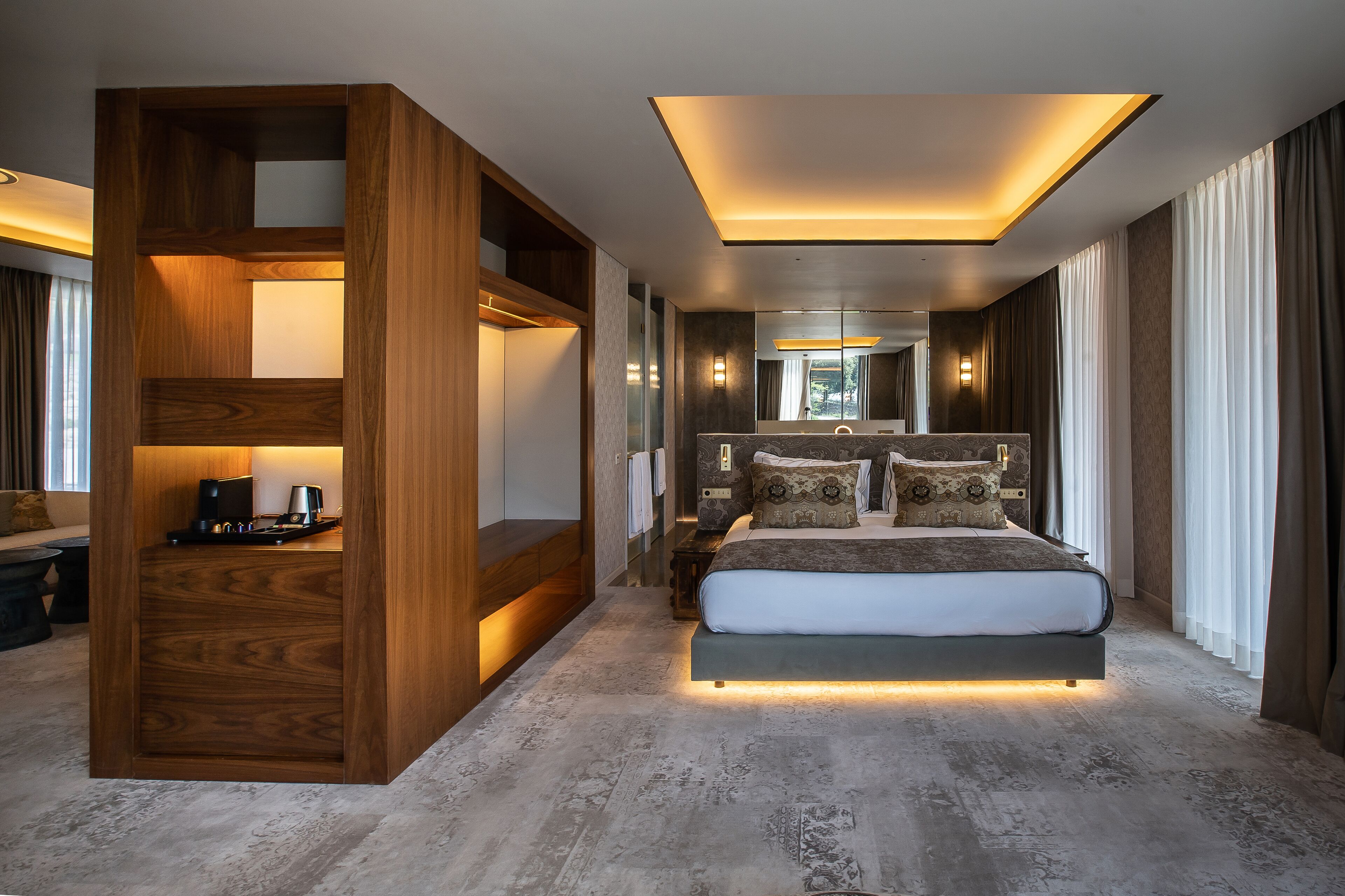 A modern bedroom with a large bed, built-in wooden shelving, and a skylight above the bed.