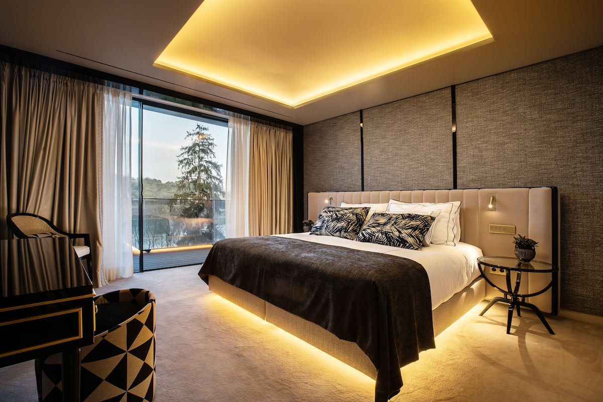 Une chambre moderne avec un grand lit, un bureau et une vue sur l’extérieur.