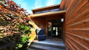 A wooden building with a stone bench and steps leading to a glass door.
