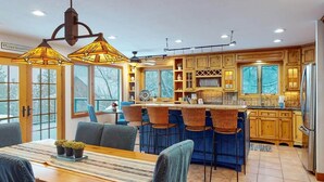 A modern kitchen with a central island, bar stools, and pendant lighting.