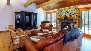 A cozy living room with a fireplace, leather sofa, and wicker chairs.
