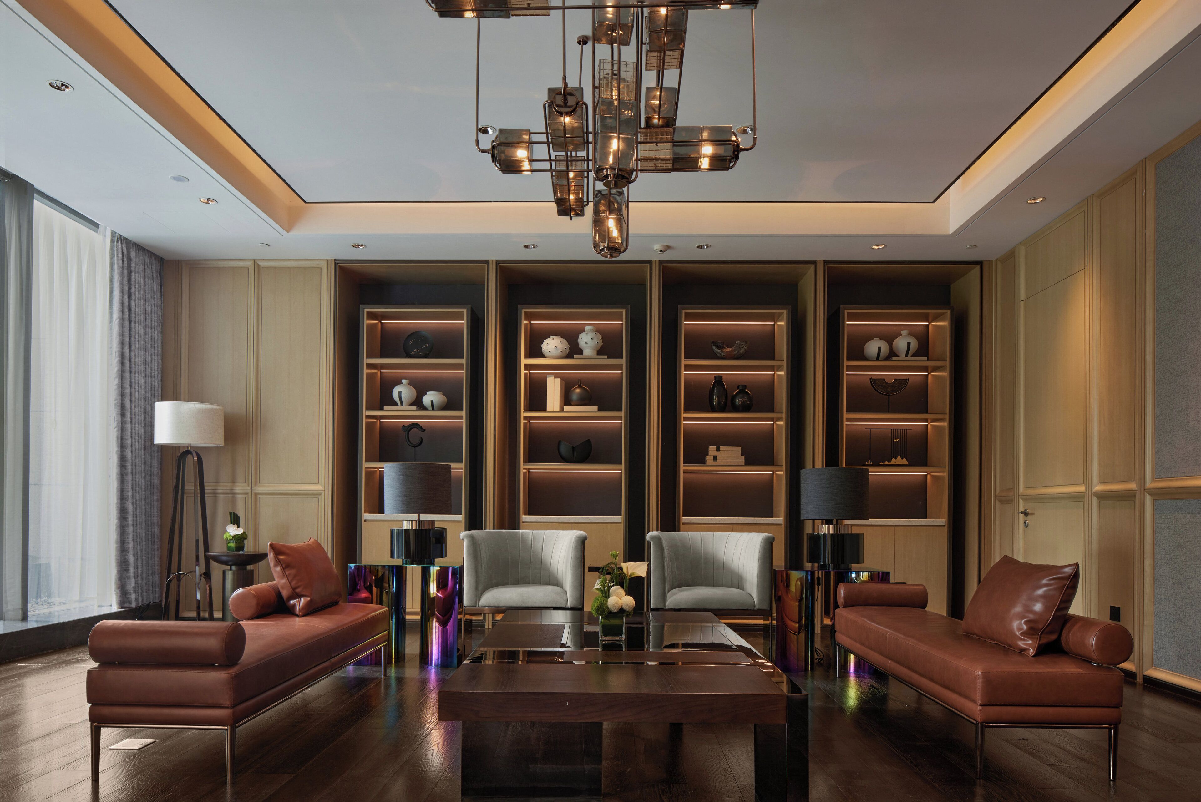 Un salon moderne comprenant un ensemble de canapés, une table basse et des étagères intégrées ornées d’objets décoratifs.