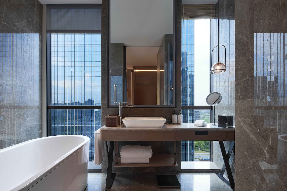 A modern bathroom with a freestanding bathtub, a large mirror, and a vanity with a sink and towel rack.