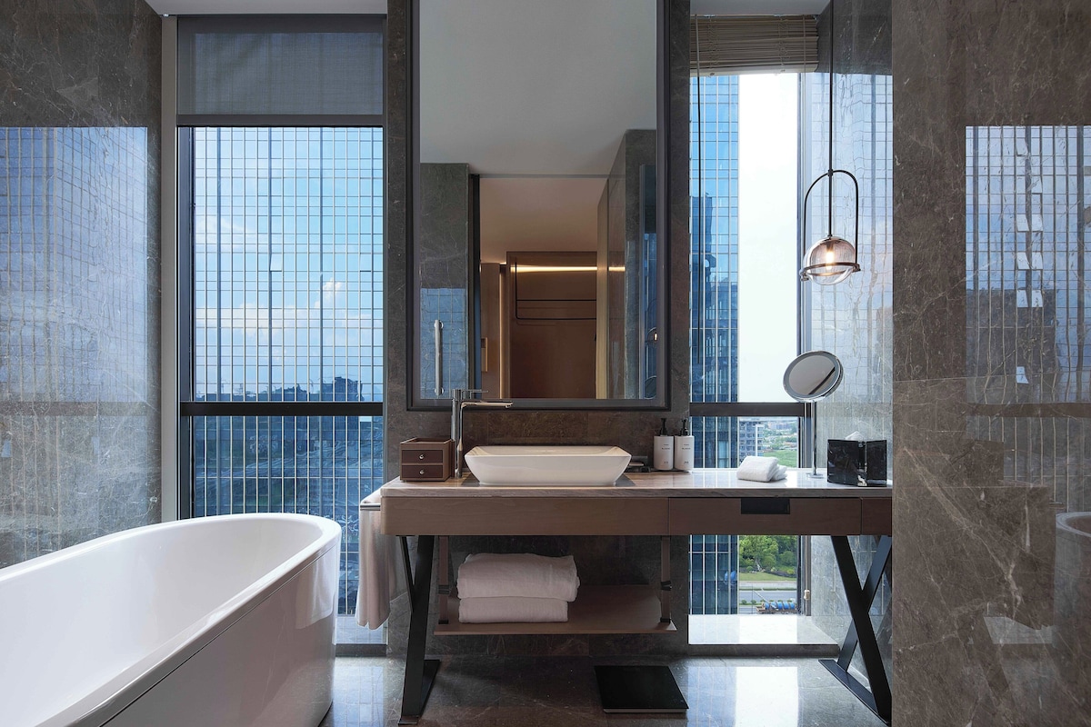 Une salle de bain moderne avec une baignoire sur pieds, un grand miroir et un meuble-lavabo doté d’un évier et d’un porte-serviettes.