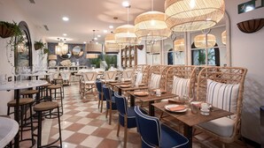 A restaurant interior with wicker furniture, checkered flooring, and pendant lighting. - Hotel Santo Cristo La Ciudadela Marbella (Marbella)