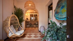 A hallway with a hanging wicker chair, a large potted plant, and a decorative wall piece. - Hotel Santo Cristo La Ciudadela Marbella (Marbella)