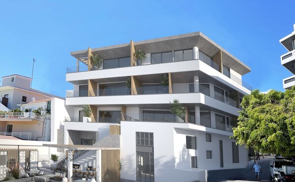 A modern multi-story building with balconies, large windows, and a flat roof.