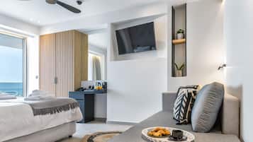 Una habitación de hotel moderna con una cama, un sofá, un televisor instalado en la pared y un pequeño escritorio con una planta.
