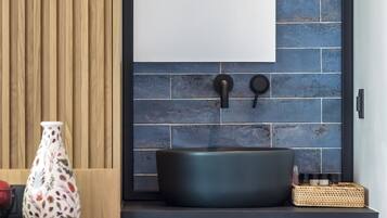 Casa de banho moderna com toucador de madeira, lavatório preto e painel de azulejos azuis.