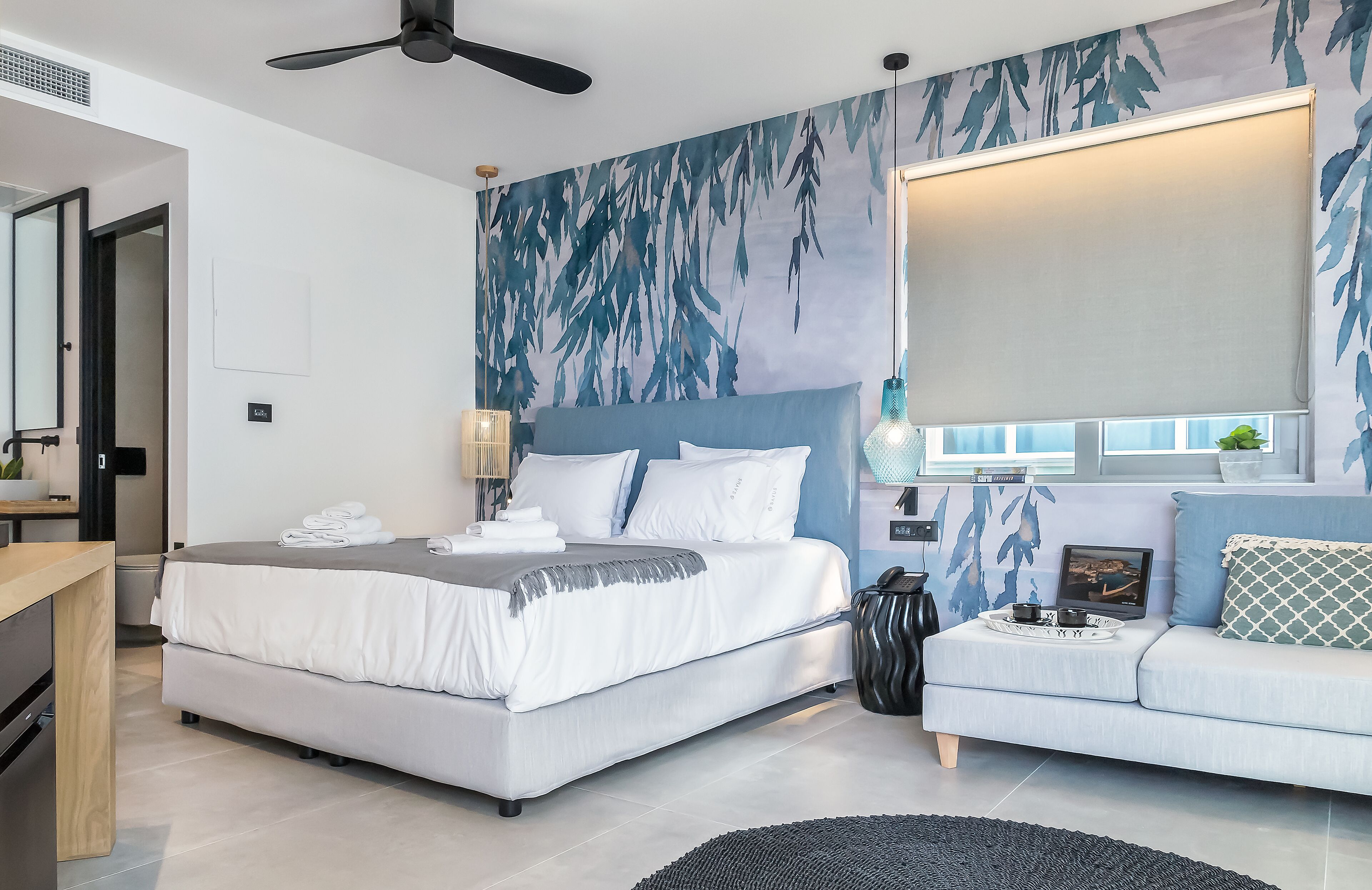 Un dormitorio moderno con cama, sofá, escritorio y un amplio ventanal.