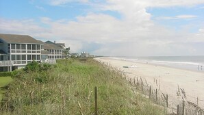 Ein Strand mit einer Rasenfläche und einem Gebäude mit vielen Fenstern.