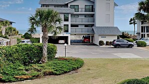 Ein mehrstöckiges Hotel mit Tiefgarage, überdachtem Parkbereich und Blick auf den Ozean.