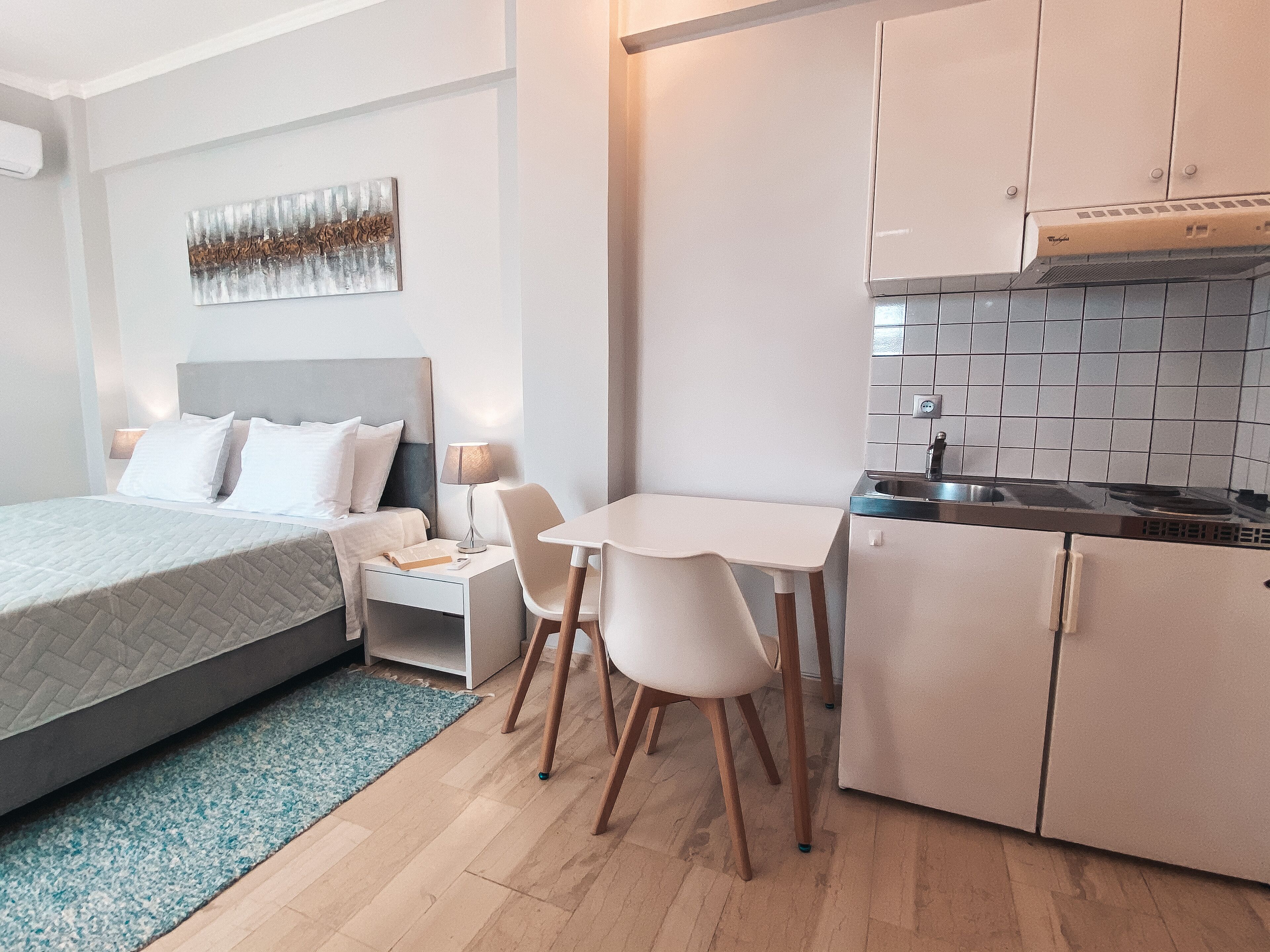 A compact hotel room with a bed, a small dining table, and a kitchenette.